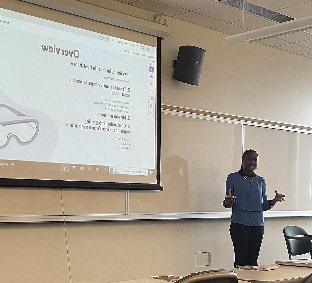 Ama Ameyaw'25 stands in front of a projector talking through a slideshow about her local healthcare experiences.